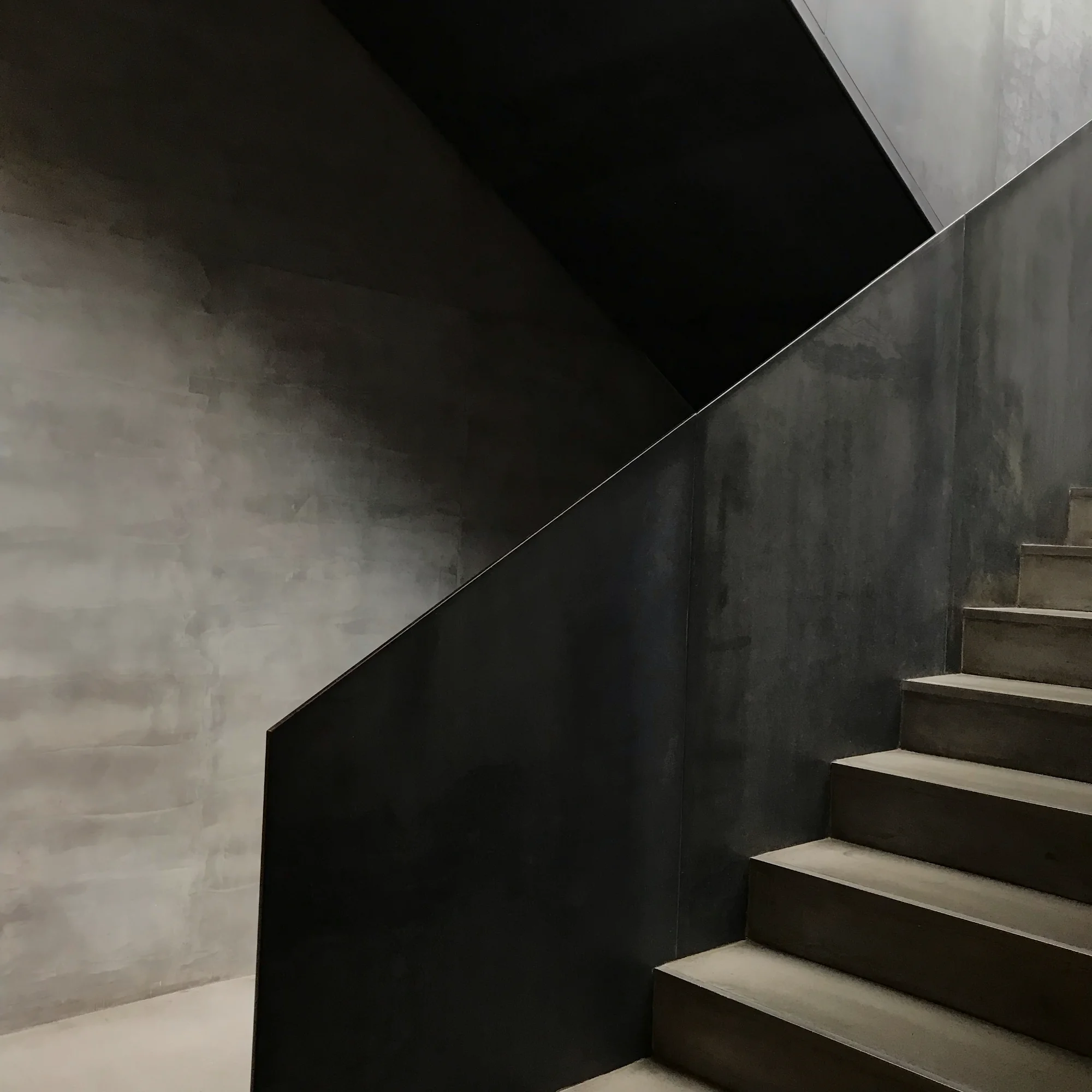 A visually striking curved staircase with a sweeping metal frame, gracefully arched stringers, and modern materials